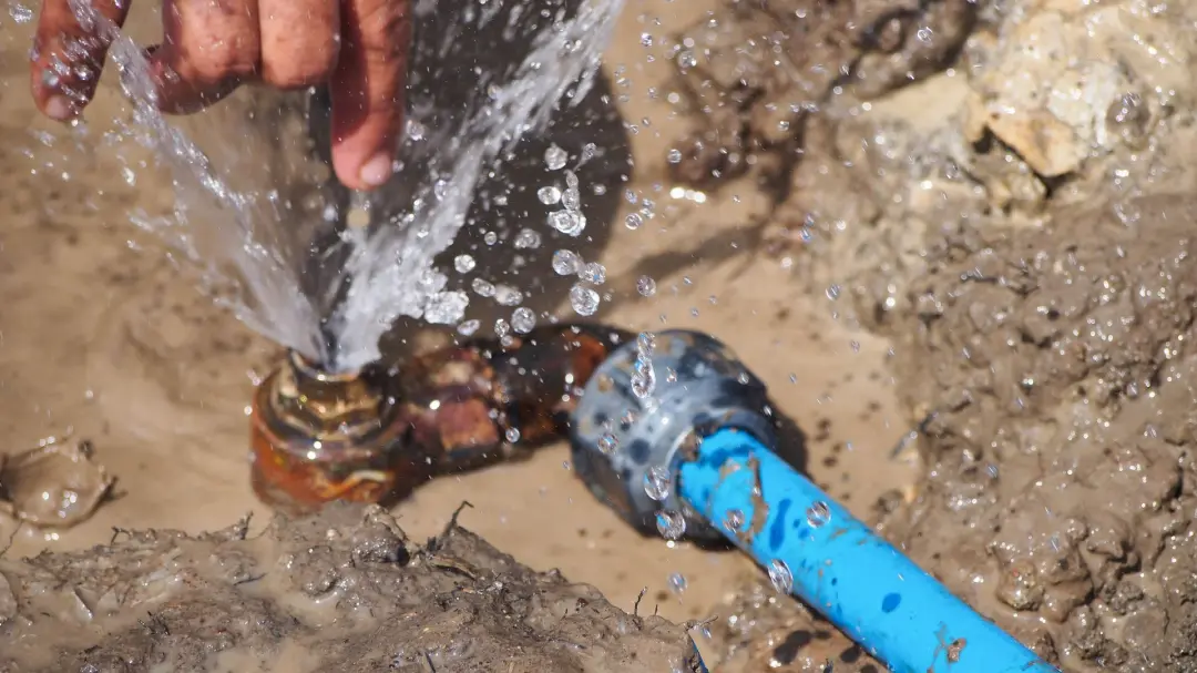 Water spraying from a burst pipe during a repair