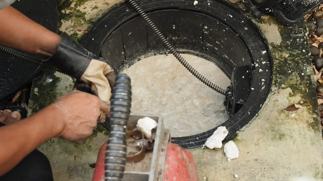 Drain auger being fed into an outdoor drain chamber