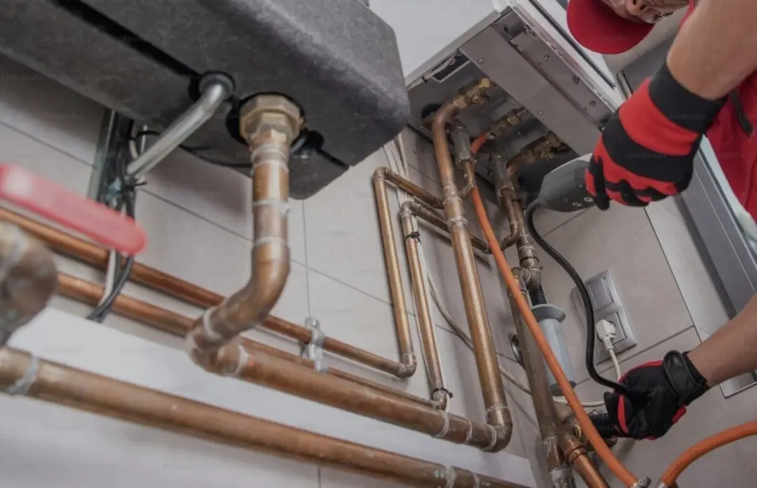Plumber in work gloves fitting copper pipework