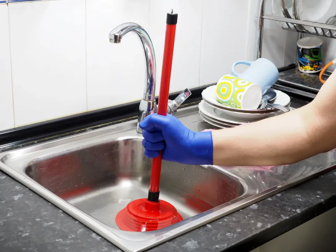Plunger clearing a blocked kitchen sink